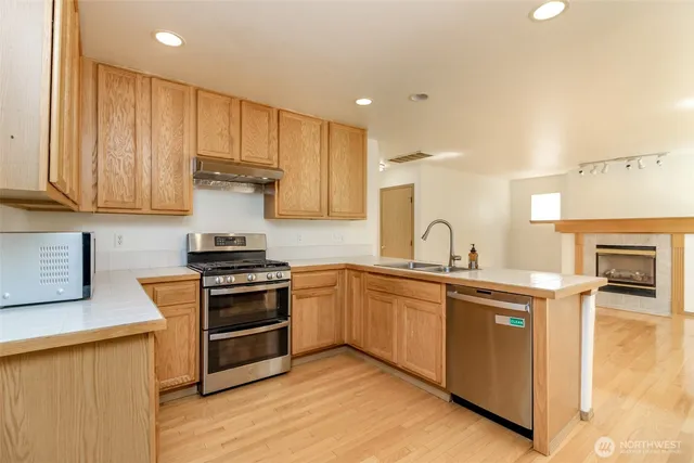 a kitchen with stainless steel appliances granite countertop a stove a sink and a microwave