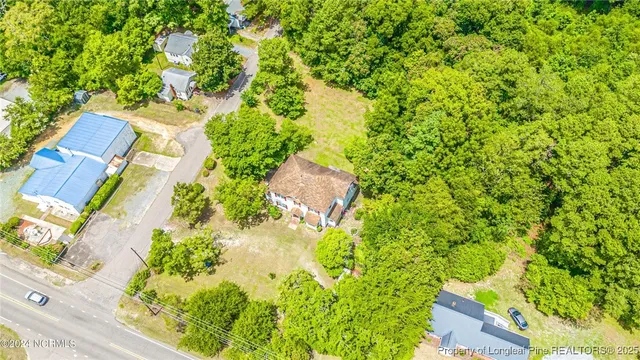 an aerial view of residential house with outdoor space and trees all around
