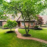 a front view of a house with garden and trees