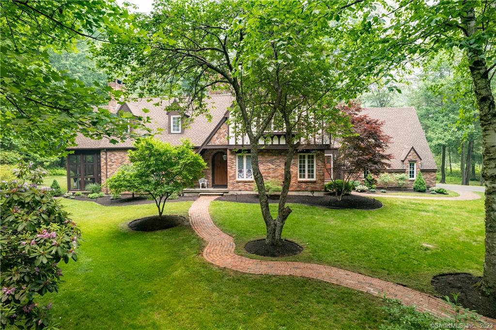 a front view of a house with garden and trees