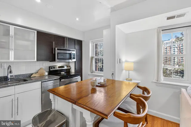 a kitchen with granite countertop a sink a counter top space cabinets and stainless steel appliances