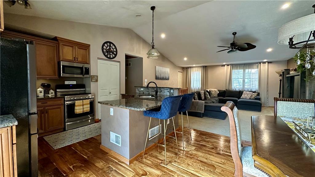 6949 Shannon Road Verona, PA 15147 - Photo 10 of 49 a kitchen with stainless steel appliances granite countertop a stove refrigerator and couches with wooden floor