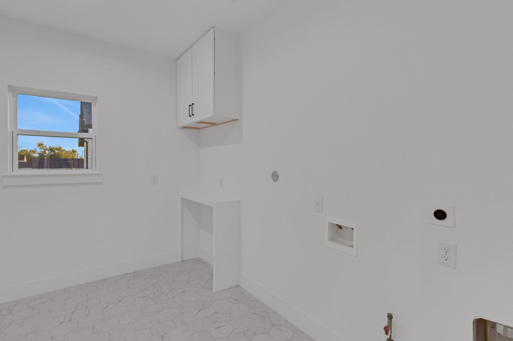 4202 Plaag Street Houston, TX 77016 - Photo 38 of 38 Oversized utility room with hexagon tile flooring, upper cabinetry, and dedicated space for washer and dryer that marries functionality with style.