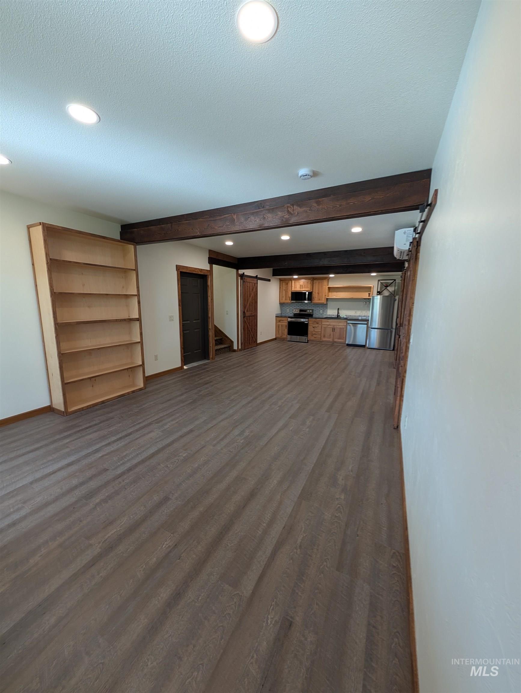 137 Angus Ranch Grangeville, ID 83530 - Photo 20 of 49 Kitchen with a barn door, open shelves, beam ceiling, stainless steel appliances, and dark countertops