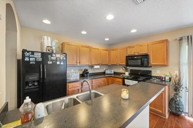 a kitchen with stainless steel appliances granite countertop a refrigerator a stove and a sink with wooden floor