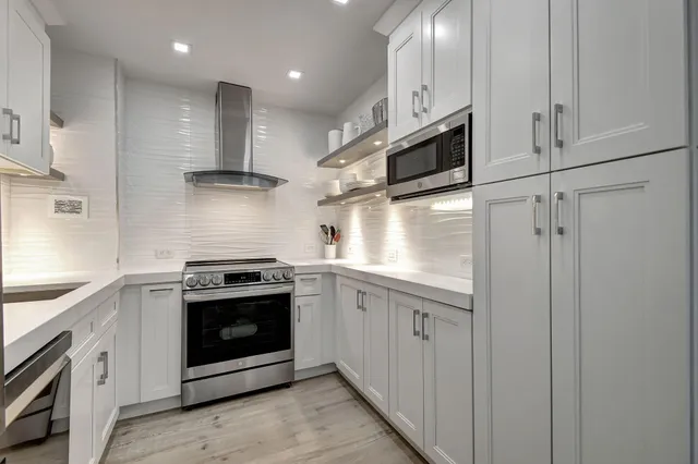 a kitchen with granite countertop a refrigerator and a stove top oven