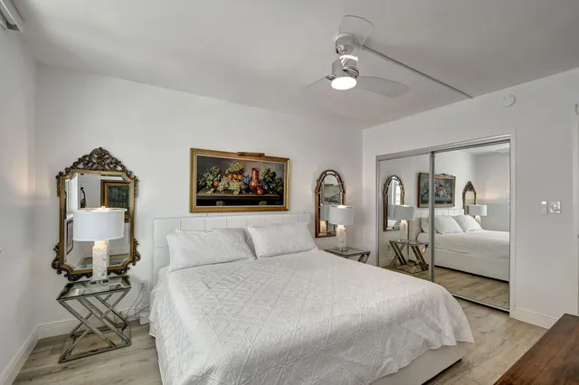 a bedroom with a bed large mirror and a window