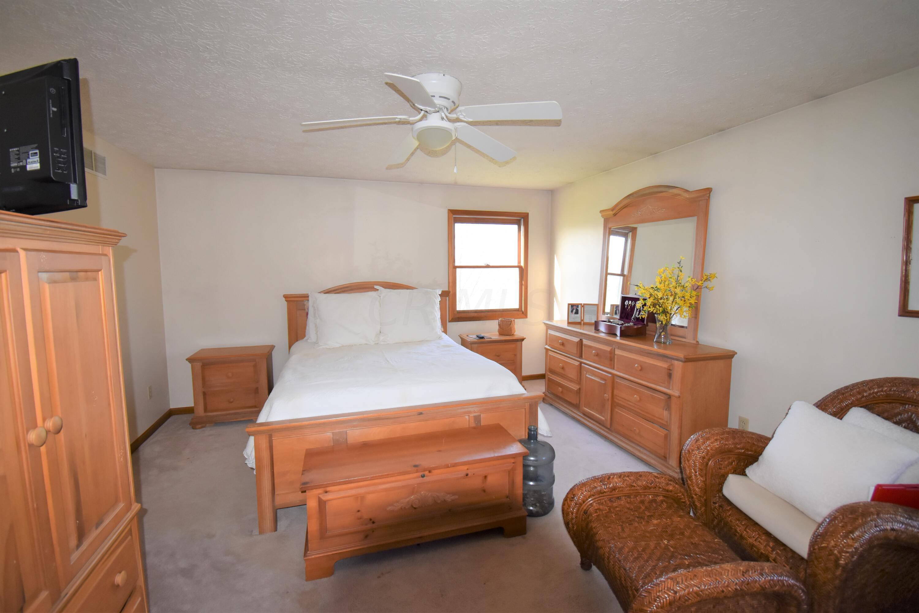 7680 Degood Road Ostrander, OH 43061 - Photo 22 of 42 16'0 x 12'5 Lovely owner's suite with lighted ceiling fan and beige carpeting.