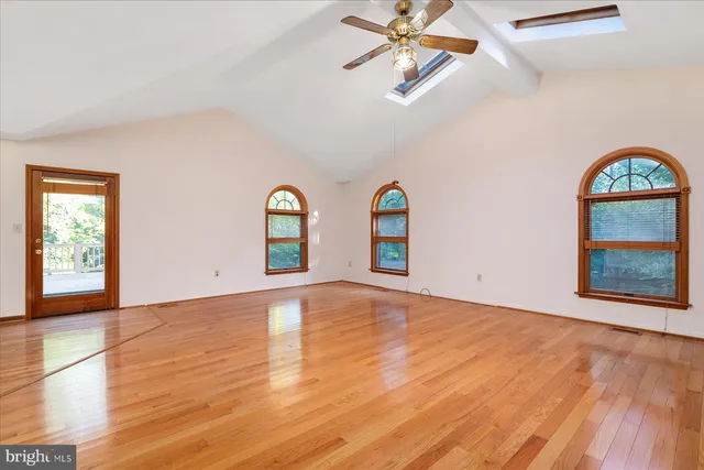 a view of an empty room with window and wooden floor
