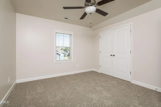 an empty room with windows and fan