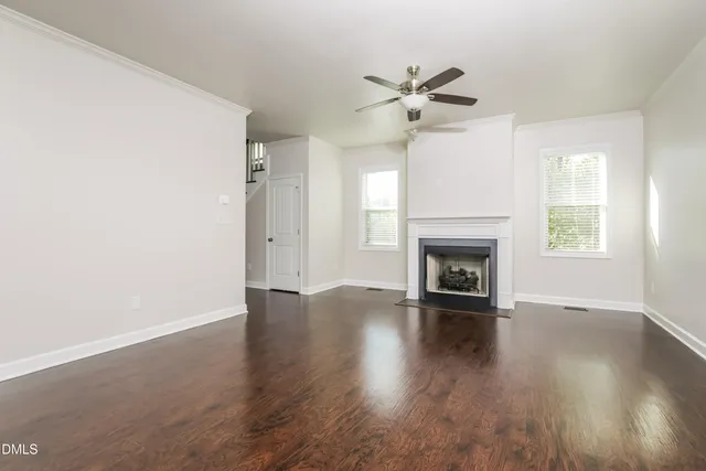 an empty room with wooden floor a ceiling fan and windows