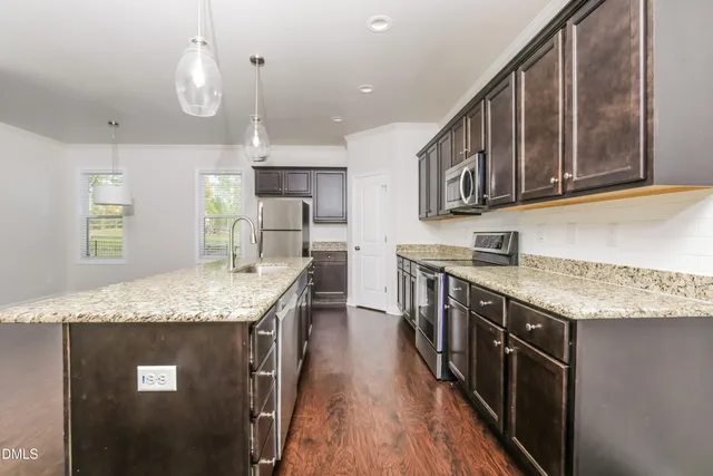 a kitchen with stainless steel appliances granite countertop a kitchen island hardwood floor sink stove and granite counter top