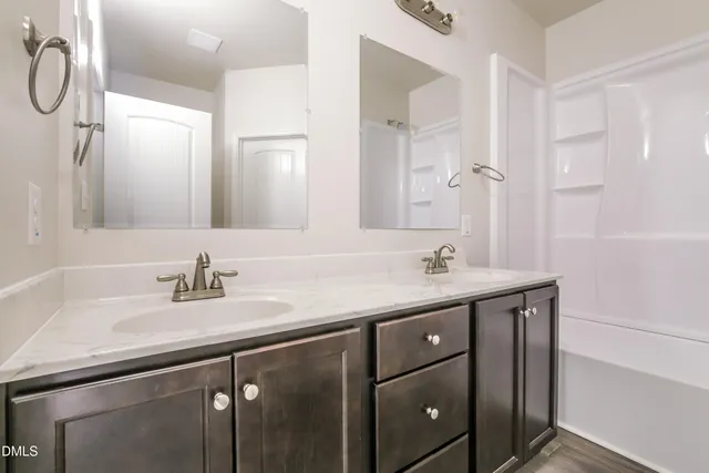 a bathroom with a double vanity sink a mirror and a shower