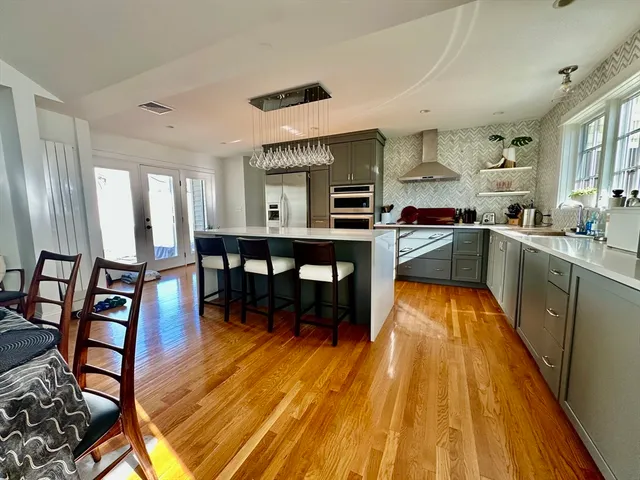 a kitchen with stainless steel appliances granite countertop wooden floors a stove and white chairs
