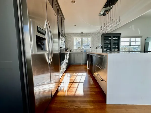 a kitchen with stainless steel appliances granite countertop a refrigerator a stove and a sink with wooden floor