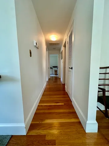 a view of a hallway with wooden floor and staircase