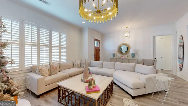 a living room with furniture a chandelier and a dining table