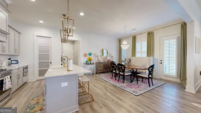 a kitchen with stainless steel appliances granite countertop a stove a sink dishwasher a dining table and chairs with wooden floor