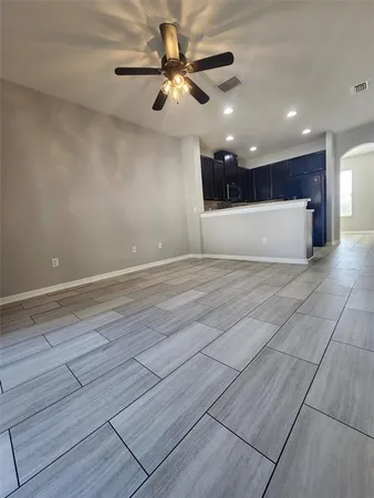 a view of an empty room with wooden floor and a ceiling fan