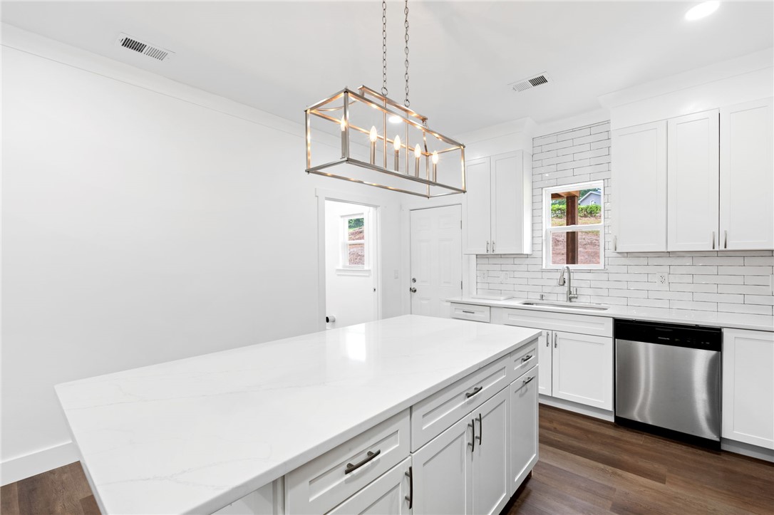 914 Smith Grove Road Easley, SC 29640 - Photo 12 of 37 A well-lit kitchen with sleek white cabinetry, a spacious island, and modern stainless steel appliances.