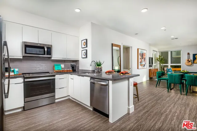 a kitchen with stainless steel appliances kitchen island granite countertop a stove top oven a sink a counter space and cabinets