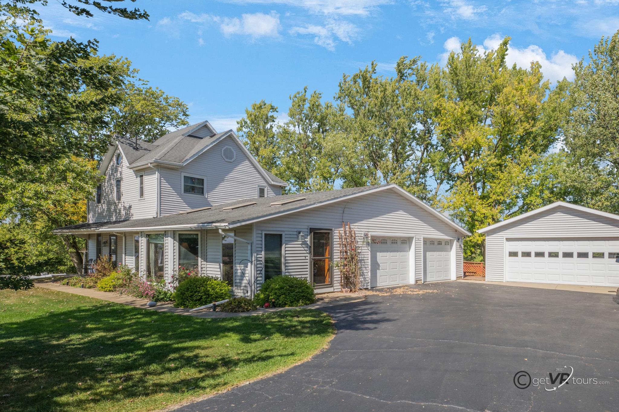 a view of a white house with a big yard and large tree