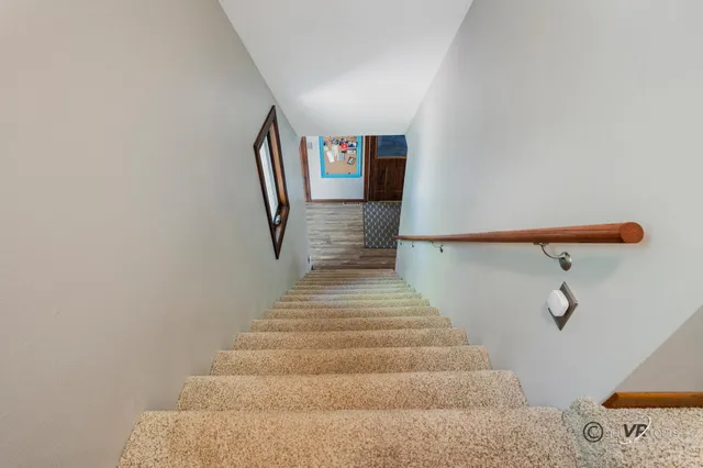 a view of a hallway with wooden floor and a bathroom