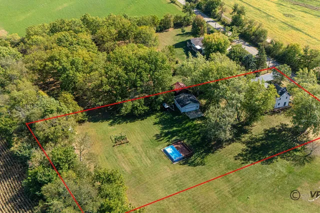 an aerial view of residential house with outdoor space and trees all around