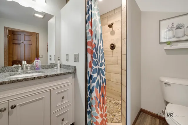a bathroom with a granite countertop sink a toilet and shower