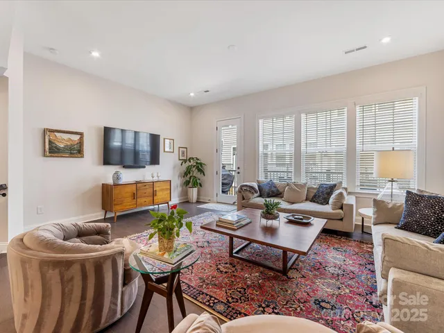 a living room with furniture a flat screen tv and a floor to ceiling window