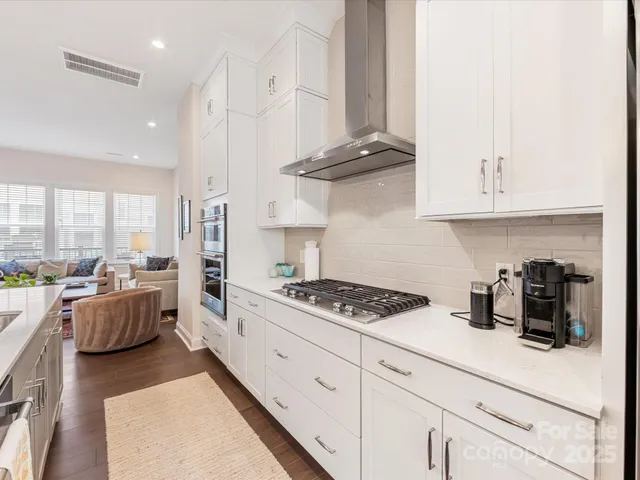 a kitchen with stainless steel appliances granite countertop a stove a sink a refrigerator and white cabinets