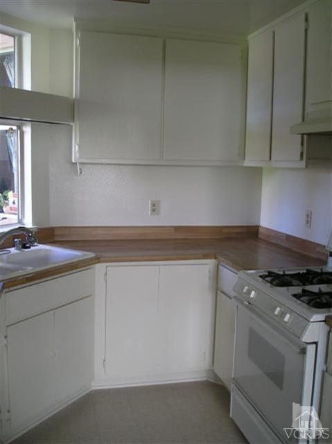 1712 Sinaloa Road, Unit 102 Simi Valley, CA 93065 - Photo 5 of 6 a kitchen with granite countertop white cabinets and white appliances