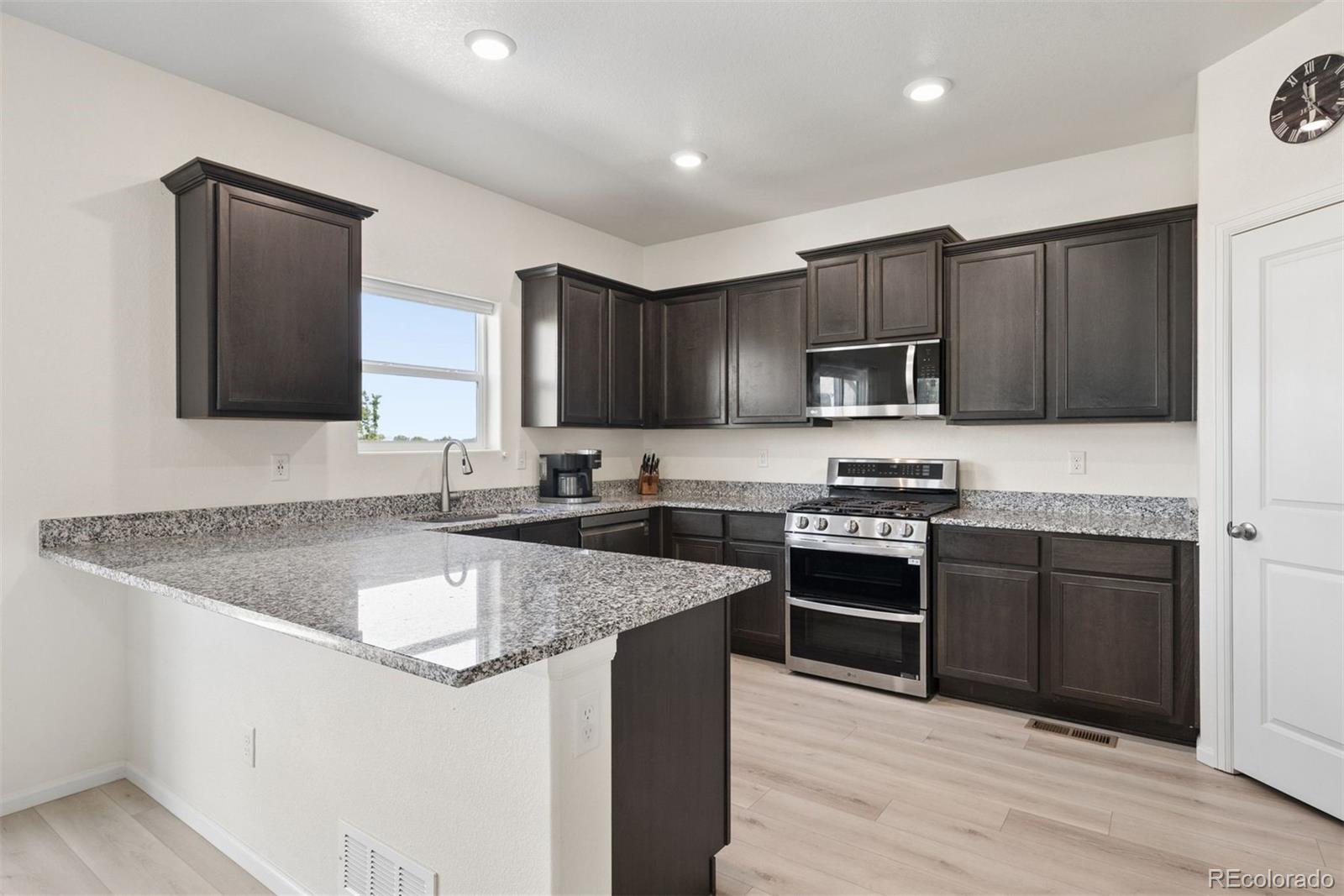 7307 Animas Avenue Frederick, CO 80530 - Photo 17 of 49 a kitchen with stainless steel appliances granite countertop a sink stove microwave and cabinets