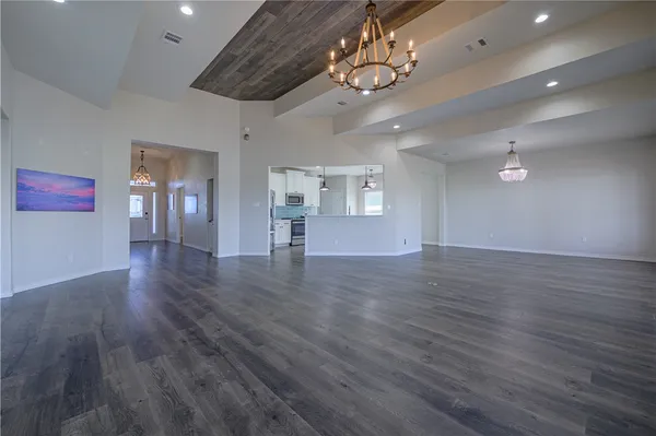 a view of an empty room with wooden floor and chandelier