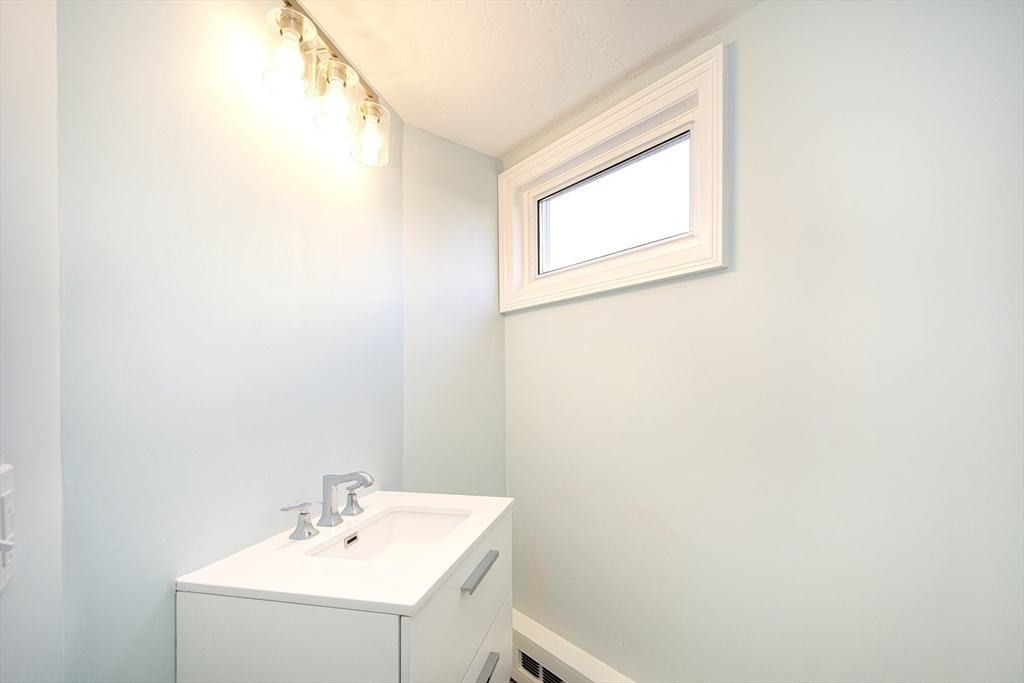7 Whitehead Avenue, Unit 1 Hull, MA 02045 - Photo 30 of 32 a bathroom with a sink a mirror and a window