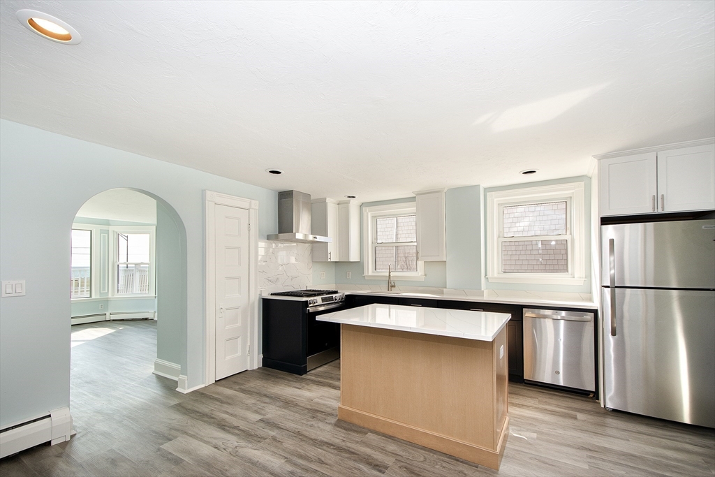 7 Whitehead Avenue, Unit 1 Hull, MA 02045 - Photo 8 of 32 a kitchen with stainless steel appliances granite countertop a refrigerator a sink a stove and white cabinets with wooden floor