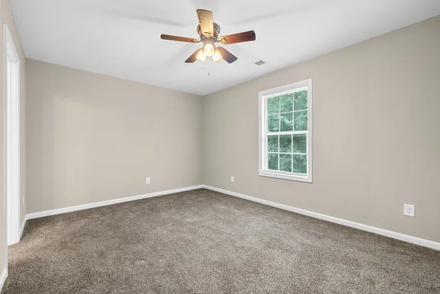 an empty room with windows and chandelier fan