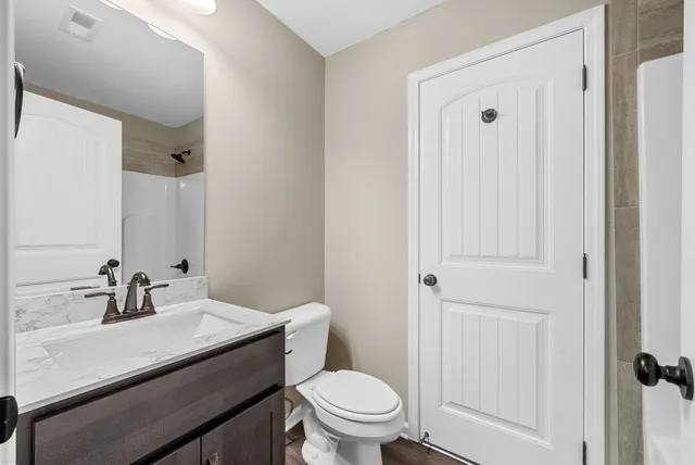 a bathroom with a sink a toilet and shower