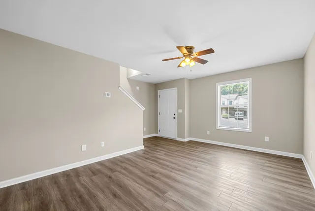 a view of an empty room with window and wooden floor
