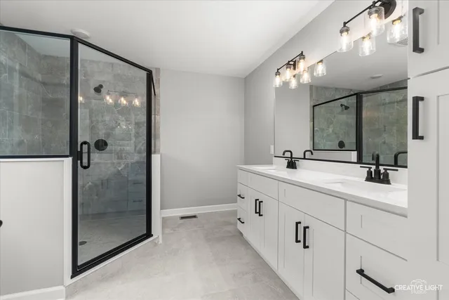 a bathroom with a double vanity sink mirror and shower