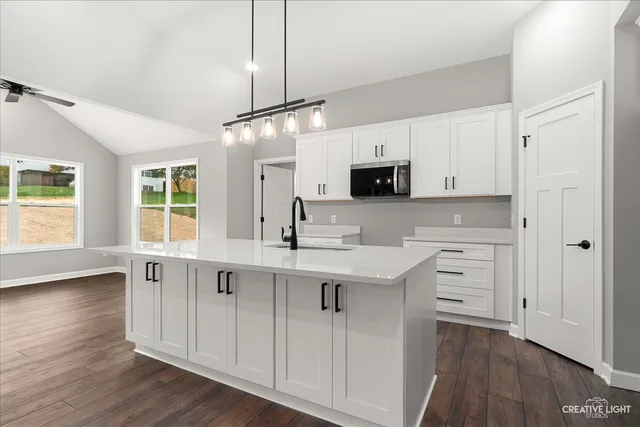 a kitchen with kitchen island granite countertop a sink cabinets and wooden floor