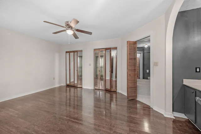 an empty room with wooden floor closet and windows