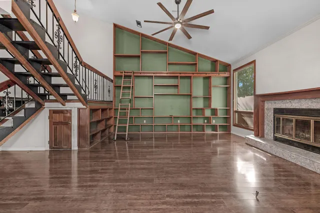 a view of a livingroom with wooden floor staircase and a kitchen space