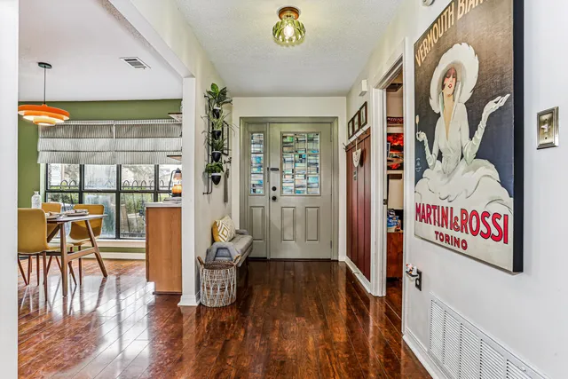 a view of a hallway to a livingroom with wooden floor and windows