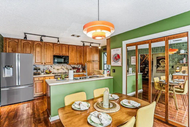 a kitchen with stainless steel appliances granite countertop a stove a refrigerator a dining table and chairs with the floor to ceiling window