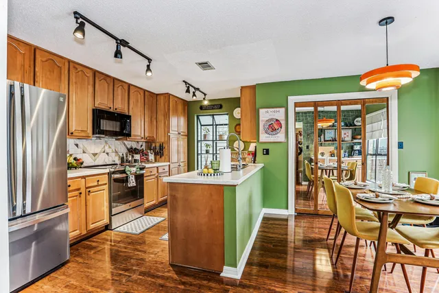 a kitchen with stainless steel appliances granite countertop a refrigerator a stove top oven a sink dishwasher and wooden cabinets