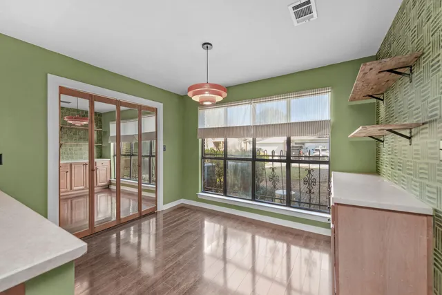 a view of an empty room with wooden floor and a window