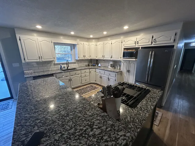 a kitchen with stainless steel appliances granite countertop a sink stove and refrigerator