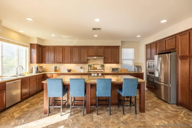 a kitchen with stainless steel appliances granite countertop a refrigerator a sink and wooden cabinets