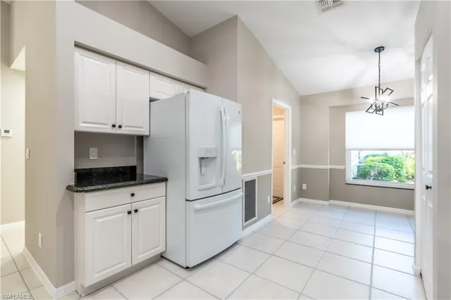 a kitchen with white cabinets and refrigerator